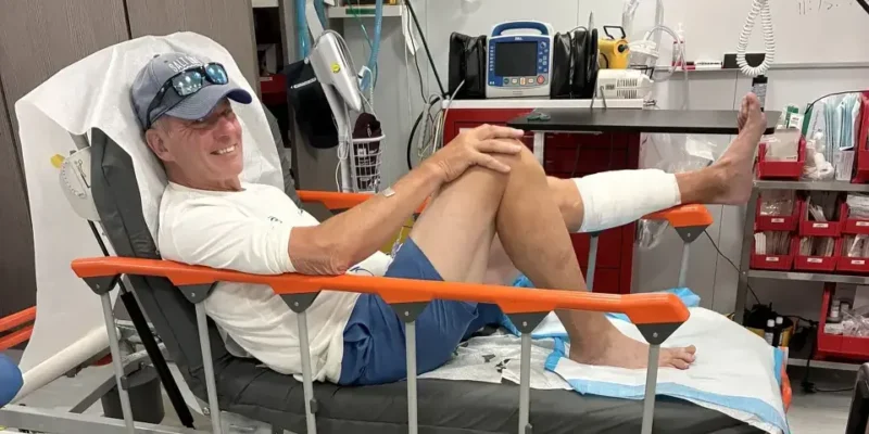 John Schweizer sitzt nach dem Hai-Biss auf den Bahamas mit verbundenem linken Unterschenkel auf einem Krankenhausbett