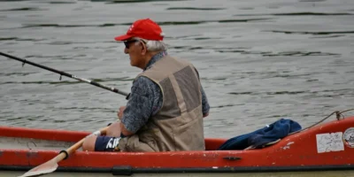 Mann mit Angelrute in einem roten Kajak auf dem Wasser