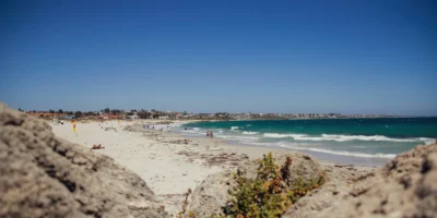Strandbesucher und Wellen am Sorrento Beach mit Felsen im Vordergrund